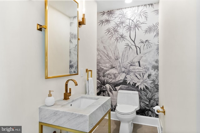 half bathroom featuring tile patterned floors, baseboards, toilet, and vanity