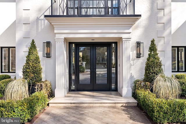 property entrance with french doors, a balcony, and stucco siding