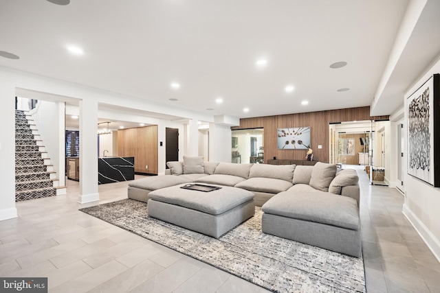 living room with wooden walls, recessed lighting, stairs, and baseboards