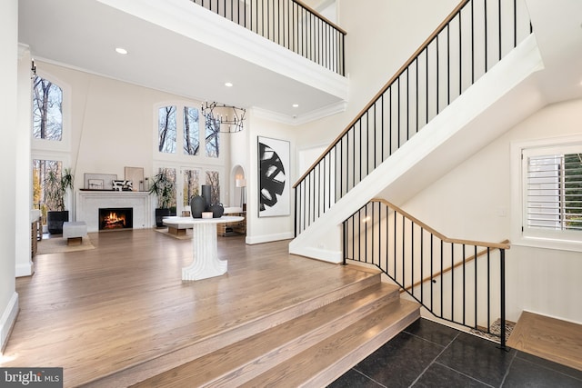 foyer entrance with a wealth of natural light, stairway, and a warm lit fireplace