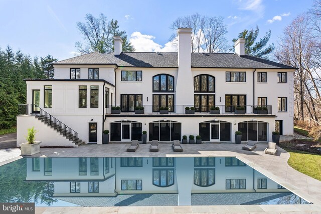 back of property with stairway, a balcony, a patio, and stucco siding