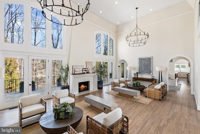 interior space featuring wood finished floors, visible vents, an inviting chandelier, arched walkways, and a lit fireplace