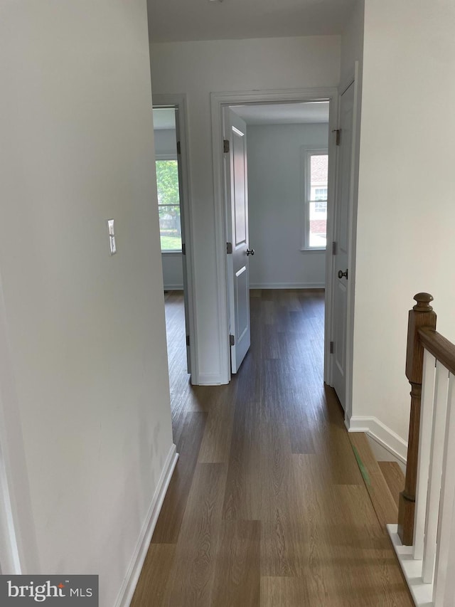 hallway with baseboards and dark wood-type flooring