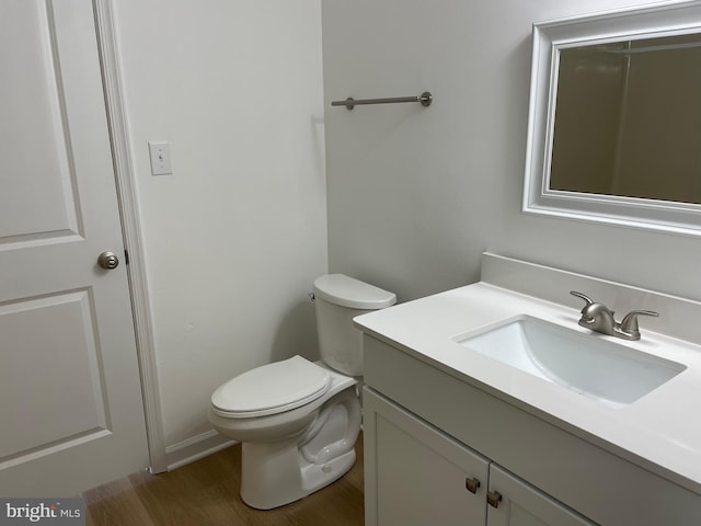 bathroom with toilet, wood finished floors, and vanity