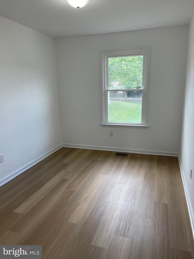 empty room featuring baseboards, visible vents, and dark wood-type flooring