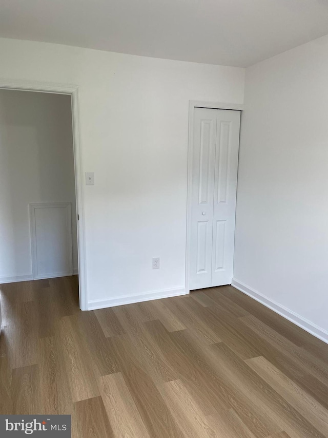 unfurnished bedroom with a closet, baseboards, and wood finished floors