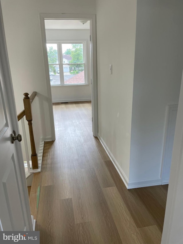 hall featuring light wood-style flooring and baseboards