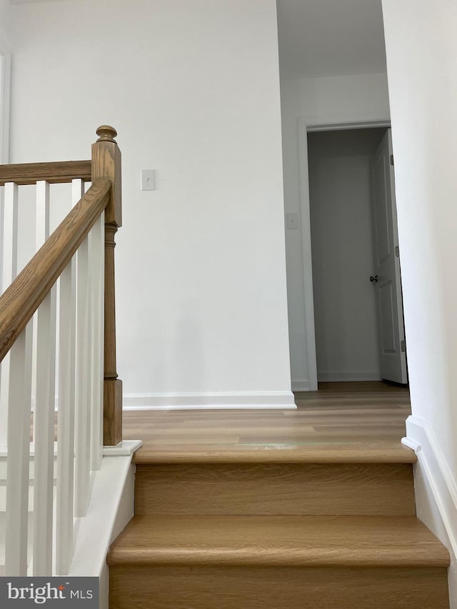 staircase with baseboards and wood finished floors