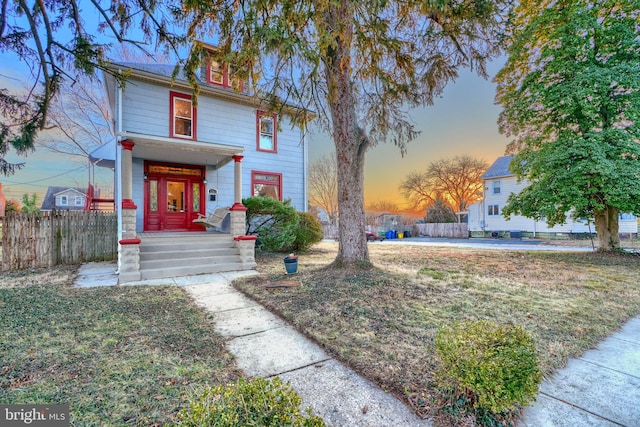 american foursquare style home featuring a yard and fence