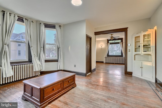 interior space with light wood-style floors, radiator, ceiling fan, and baseboards