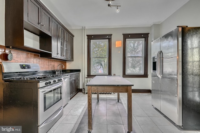 kitchen with stainless steel appliances, decorative backsplash, light tile patterned flooring, dark brown cabinetry, and baseboards