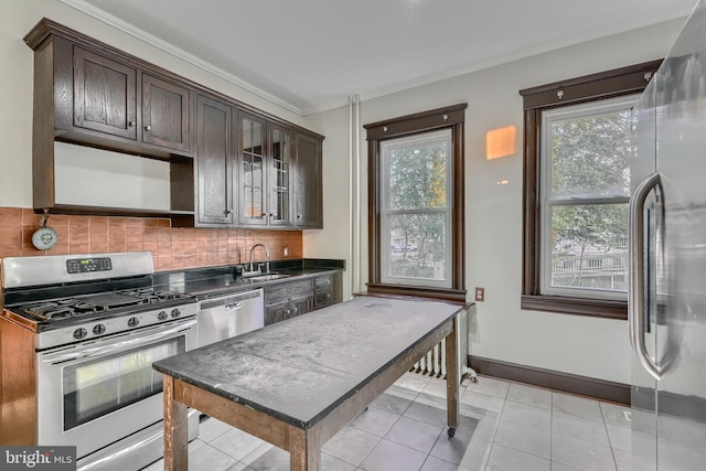 kitchen featuring dark countertops, decorative backsplash, glass insert cabinets, appliances with stainless steel finishes, and dark brown cabinetry