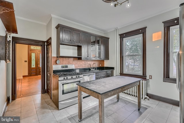 kitchen with stainless steel appliances, dark countertops, glass insert cabinets, a sink, and dark brown cabinets