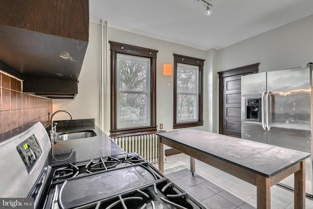 kitchen featuring light tile patterned floors, stainless steel fridge, decorative backsplash, radiator, and a sink