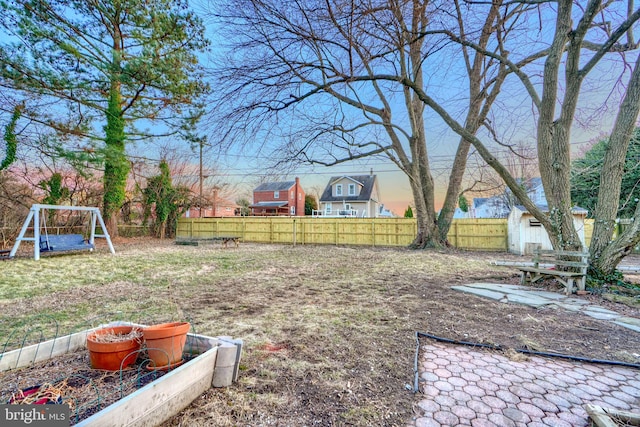 view of yard featuring a vegetable garden, fence, an outdoor structure, and a shed