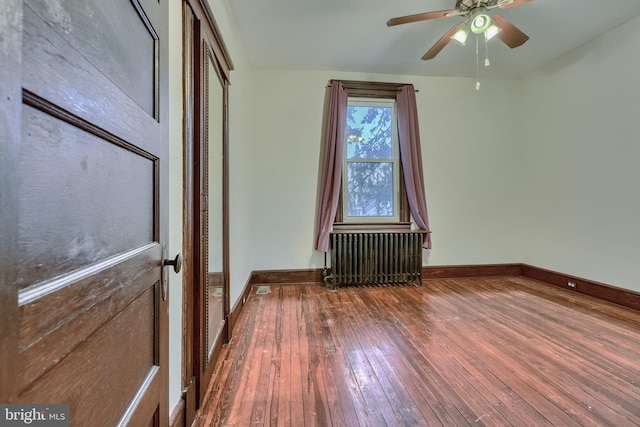 interior space featuring dark wood-style floors, baseboards, a ceiling fan, and radiator