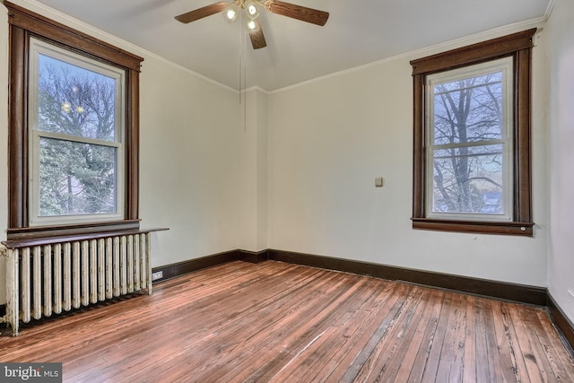 unfurnished room featuring crown molding, baseboards, wood finished floors, and radiator