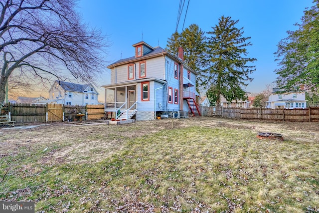 rear view of property featuring cooling unit, a fenced backyard, a lawn, and a chimney