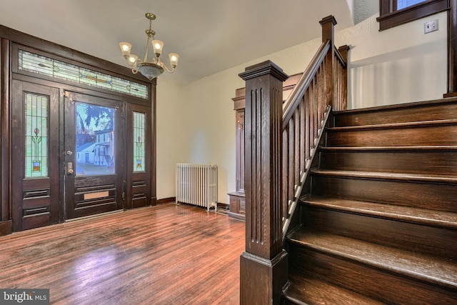 entryway featuring a notable chandelier, baseboards, stairway, radiator heating unit, and dark wood finished floors