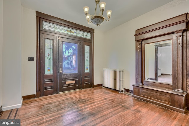 entrance foyer featuring a chandelier, radiator heating unit, wood finished floors, and baseboards