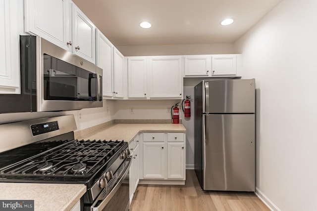 kitchen featuring light wood-style flooring, appliances with stainless steel finishes, light countertops, white cabinetry, and recessed lighting