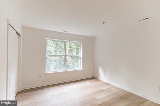 unfurnished bedroom with light wood-type flooring, a closet, visible vents, and baseboards