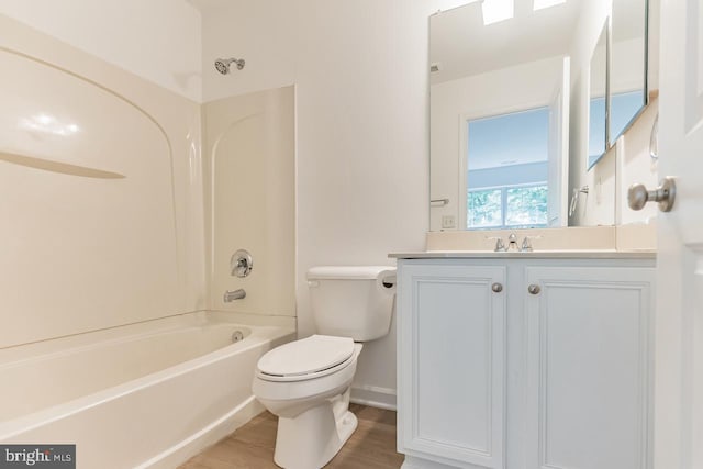 bathroom with toilet, vanity, wood finished floors,  shower combination, and baseboards