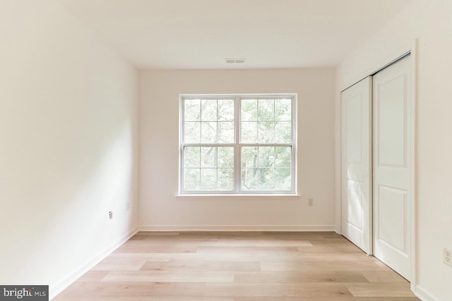 unfurnished bedroom with light wood-style floors, a closet, visible vents, and baseboards