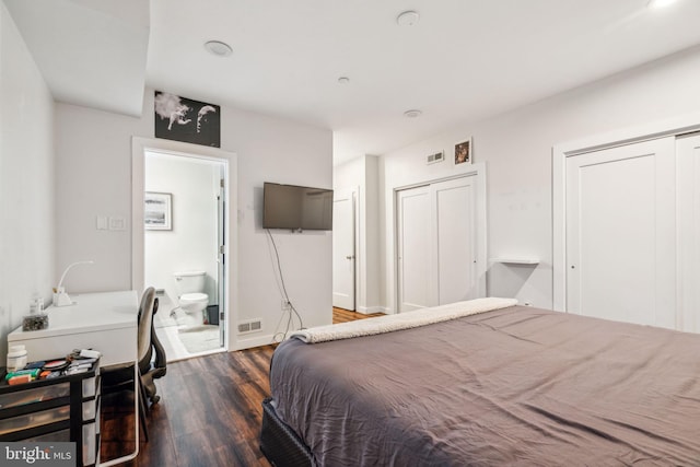 bedroom featuring connected bathroom, visible vents, dark wood finished floors, and multiple closets