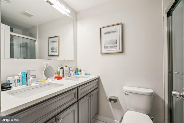 bathroom featuring toilet, a stall shower, a sink, and visible vents