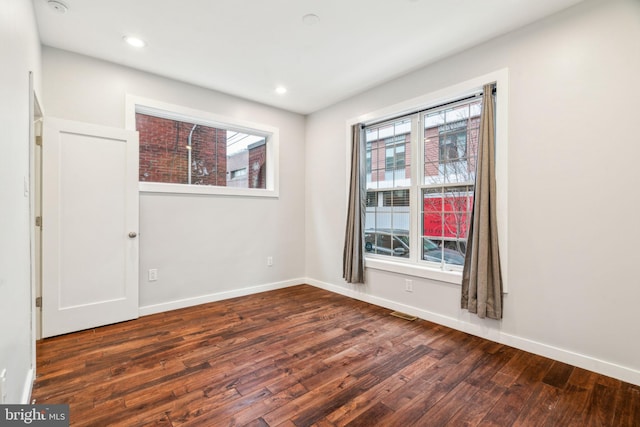 empty room featuring baseboards, hardwood / wood-style floors, and recessed lighting