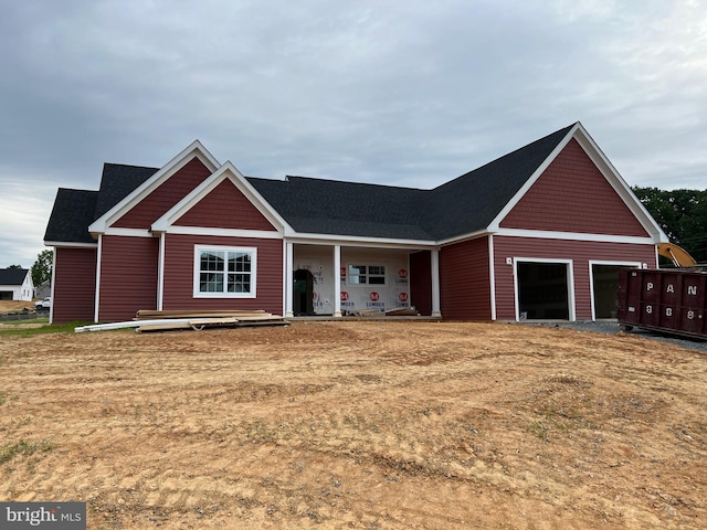 view of front of house with a garage, covered porch, and a front yard