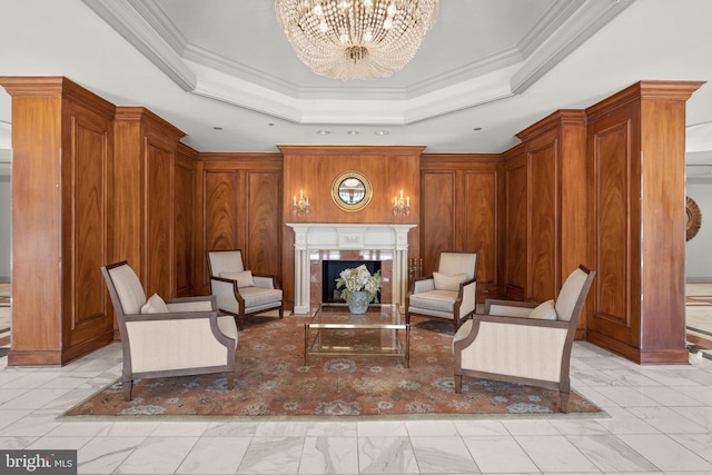 living area with wood walls, a fireplace, a raised ceiling, and a notable chandelier