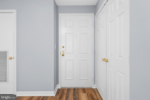 doorway featuring dark wood-style floors and baseboards