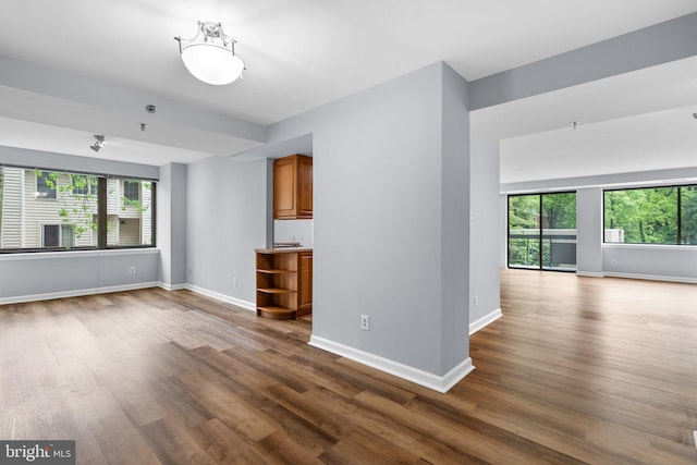 unfurnished living room featuring dark wood finished floors and baseboards