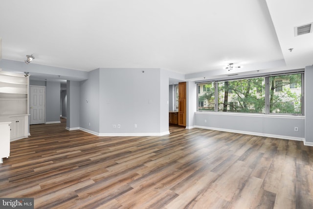 unfurnished living room featuring dark wood-type flooring, visible vents, and baseboards