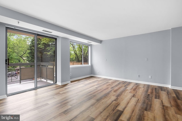 unfurnished room featuring visible vents, baseboards, and wood finished floors