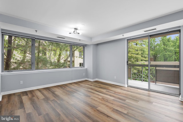 unfurnished room featuring baseboards, visible vents, and wood finished floors