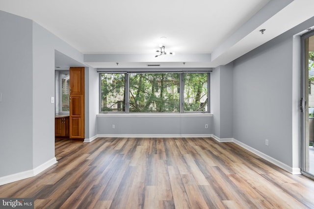 empty room featuring dark wood-style flooring, visible vents, and baseboards