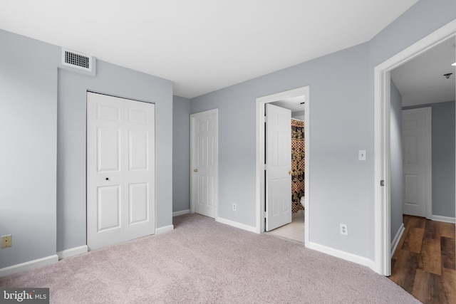 unfurnished bedroom featuring baseboards, a closet, visible vents, and light colored carpet