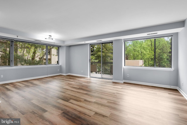 unfurnished room featuring baseboards, a wealth of natural light, and light wood-style floors