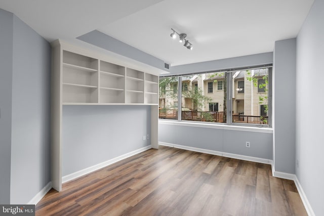 empty room featuring wood finished floors, visible vents, and baseboards