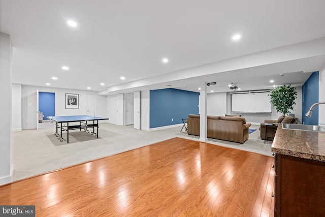 rec room featuring recessed lighting, baseboards, a sink, and light wood finished floors