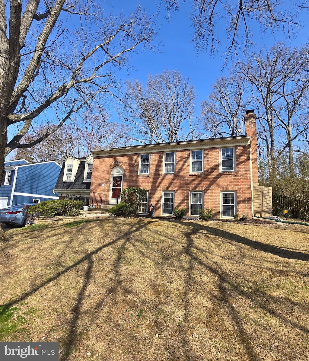 view of front of property featuring a front lawn, brick siding, and a chimney