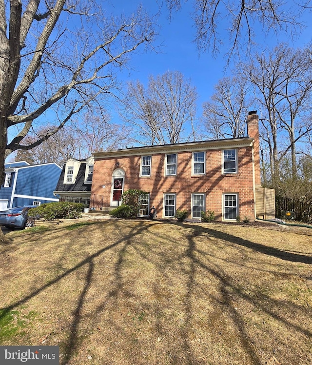 view of front of property featuring a front lawn, brick siding, and a chimney