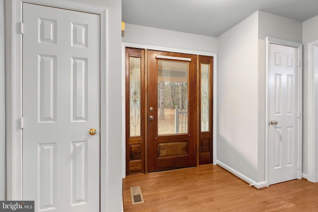 foyer entrance with light wood-type flooring, visible vents, and baseboards