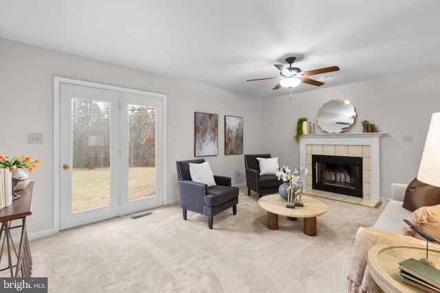 carpeted living area with baseboards, a fireplace, visible vents, and a ceiling fan