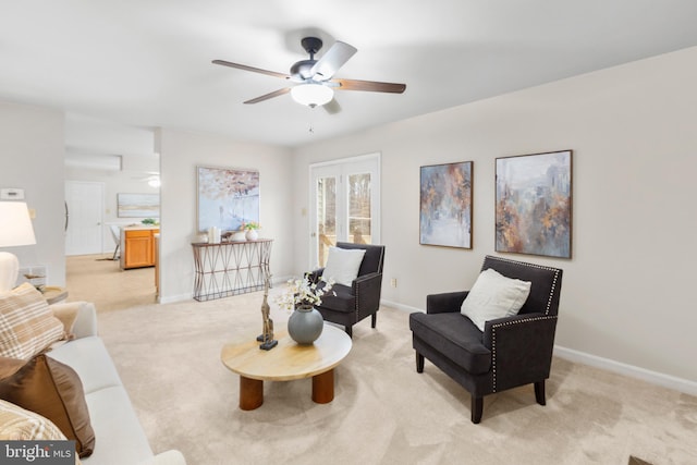 living area with baseboards, a ceiling fan, and light colored carpet