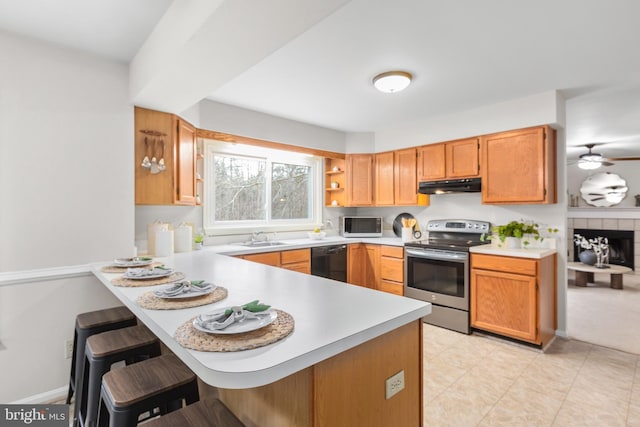 kitchen featuring under cabinet range hood, a peninsula, a sink, black dishwasher, and stainless steel electric stove