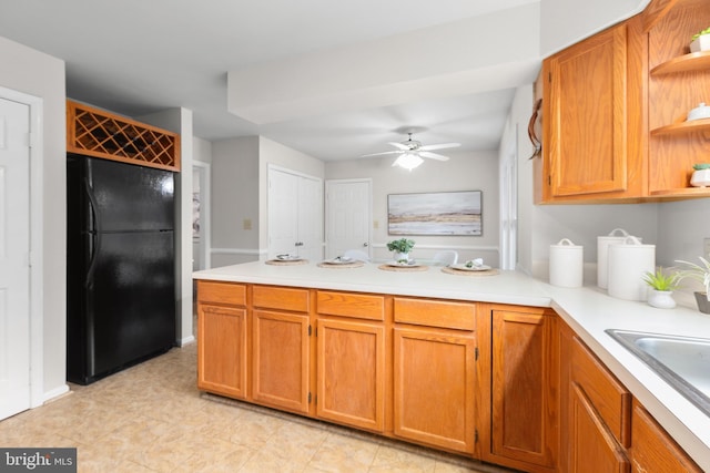 kitchen with open shelves, a peninsula, light countertops, and freestanding refrigerator